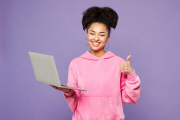Young fun IT woman of African American ethnicity wear pink hoodie casual clothes hold use work on...
