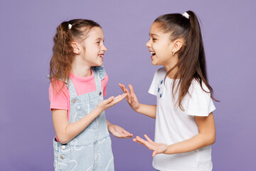 Little smiling cheerful cool two friends kids children girls 9-10 years old wear casual clothes together talking with each other laugh have fun isolated on plain purple background. Lifestyle concept.