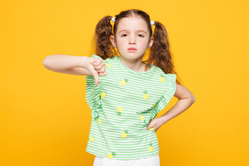 Little sad disappointed kid child girl 8-9 years old wears green t-shirt showing thumb down dislike...
