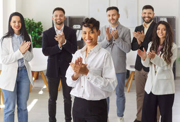 Group of diverse happy business people men and women looking at the camera, smiling and applauding....