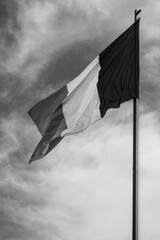 National flag of Romania flying in the wind; black and white version of the red yellow and blue...