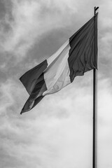 National flag of Romania flying in the wind; black and white version of the red yellow and blue flag on clear sky background