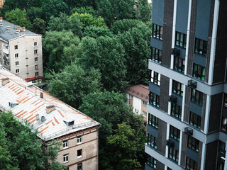 Contrast of old Soviet apartment buildings and modern residential tower surrounded by green trees....