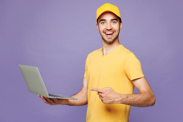 Young fun delivery guy employee IT man wear yellow cap t-shirt uniform workwear work as dealer...