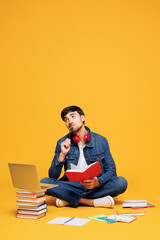 Full body young boy student in casual clothes sit near backpack bag books write down notes in notebook diary use laptop pc isolated on plain yellow background. High school university college concept.