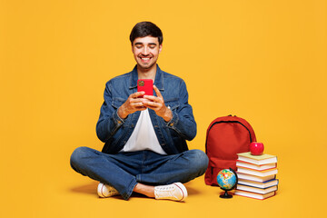 Full body young happy boy student wear denim casual clothes sit near backpack bag books hold in...