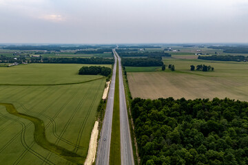 Lonely road cutting through vast field.