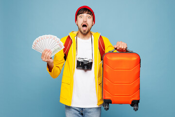 Traveler man wear hat yellow casual clothes hold fan of cash money bag isolated on plain pastel...