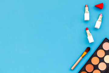 Flatlay of makeup cosmetics on blue background. Blusher, mascara and lipstick, top view