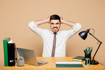Young sad mistaken shocked employee business man wear white shirt tie sit work at office desk with...