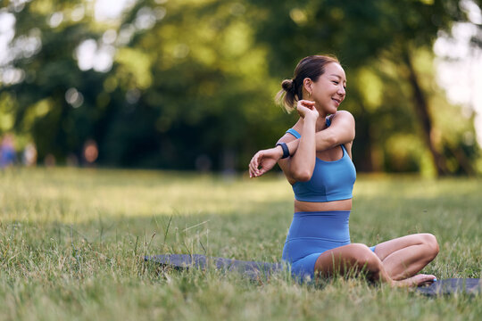 Woman Stretching Outdoors in a Park During Daytime Wearing Blue Fitness Outfit