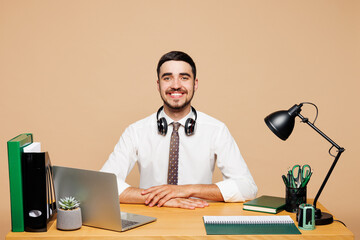Young smiling happy successful employee business man wear white shirt tie headphones sit work at...