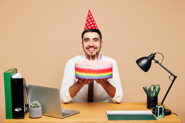 Young happy successful employee business man wear white shirt tie birthday hat sit work at office...