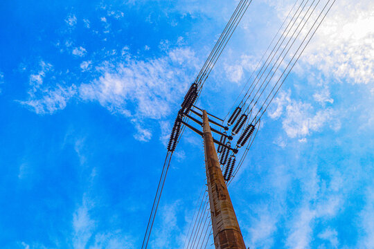 Electric Tower, High Voltage Power Line for Electricity Distribution with white clouds and blue sky background