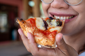 Close-up of woman enjoying cheesy pizza slice with tomato sauce and toppings, happy dining moment...