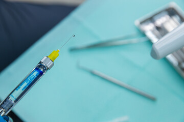 Close-Up of a Syringe with a Yellow Cap and Blue Liquid Ready for Injection on a Medical Table...
