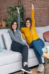Obraz premium Smiling young women friends looking at camera sitting on couch in the living room at home.