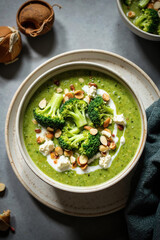 Indulge in Vibrant Green Wellness: Creamy Broccoli and Cauliflower Soup, Richly Topped with Crunchy Almonds and Fresh Florets, Offering a Nutritious and Comforting Vegetarian Delight.
