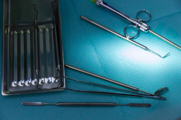 A Close-Up View of Surgical Instruments on a Blue Surgical Drape with Glare Highlighting Their...