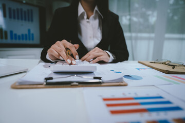 A professional businesswoman calculates financial data using a calculator, surrounded by charts and reports, analyzing company performance to ensure growth, profitability, and strategic business decis