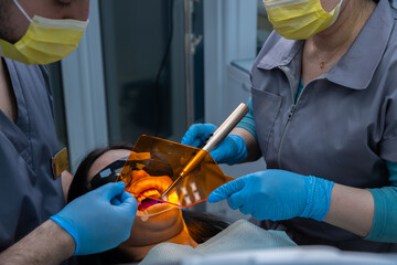 Dental professionals performing a treatment in a modern dental clinic with advanced equipment, ensuring patient comfort and safety during oral procedures.