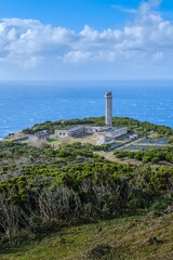 Majestic Lighthouse and Associated Buildings Perched on a Lush Green Cliffside Overlooking Vast Atlantic Ocean on Sao Jorge Island, Azores. Coastal Landmark, Scenic View, Maritime Heritage, Portugal