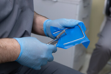 Healthcare Professional Preparing Surgical Instrument with Blue Barrier for Sterilization in...