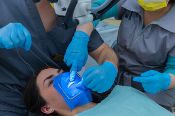 A dental procedure being performed with precision as a female patient lies on the examination chair...
