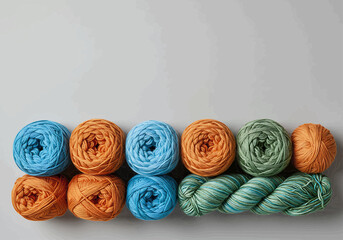 Arrangement of ten yarn balls in blue orange and green colors on a gray surface in a studio setting