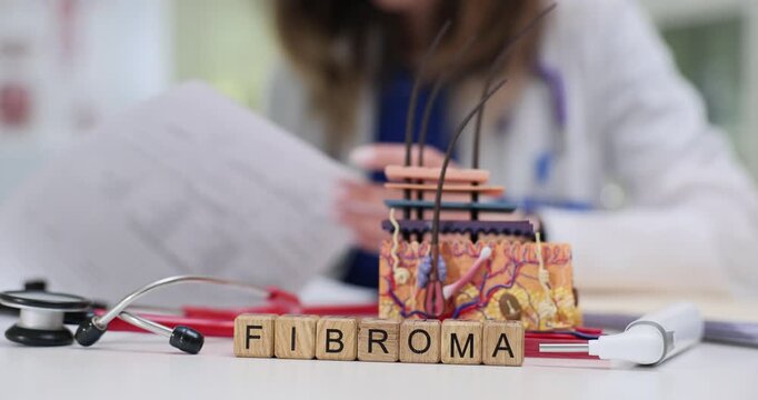 Word Fibroma near anatomical model of skin and woman writes prescription for treatment. Benign tumors composed of fibrous and connective tissue
