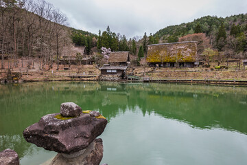 Serene view of Shirakawa-go's Gassho-style farmhouses reflected in a calm pond. Traditional...