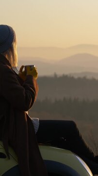 Vertical Video of Blonde European Girl on Car Hood with Tea Mug
