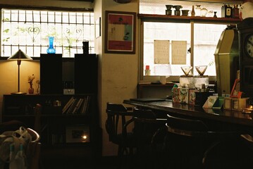Cozy vintage-style café interior with warm lighting, bookshelves, and eclectic decor near a sunlit window