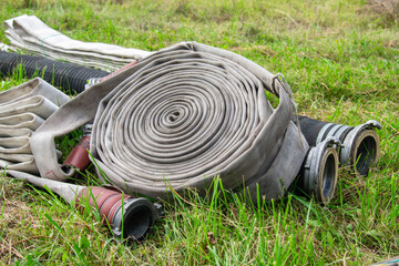 Fire hose rolled up on lawn, lying on grass