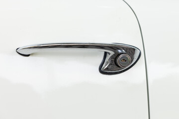 Close-up of a chrome door handle of a white classic car