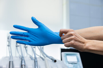 Close-Up of a Dental Professional Donning Blue Gloves in a Modern Dental Office, Ready for Patient...