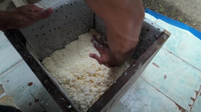 A person pressing and molding fresh cheese curds, typical in the making of queso llanero from Venezuela