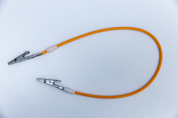 Close-Up of an Orange Jumper Cable with Metal Clips: Essential Tool for Battery Connections and...