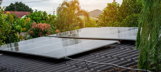 Solar panels installed on a house roof surrounded by lush green trees, clean renewable energy...