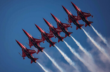 Seven fighter jets flying in formation, leaving white trails behind them against the blue sky