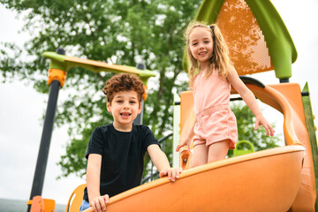 Happy kids on slide on playground on summer season