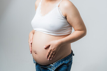 Woman is putting hands in heart on pregnant tummy on white background. Happy pregnancy, motherhood, maternity. Gental parenting concept. Close-up