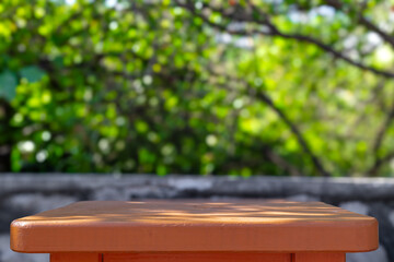 Wooden table in sunny summer day with green leaves bokeh blurred background. Table ads mock up for...