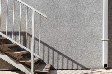 gray empty concrete wall with sunlight and shadows with stairs in summer day minimalistic...