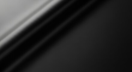 Abstract black and gray fabric draping softly, creating smooth curves and shadows in a minimalist setting