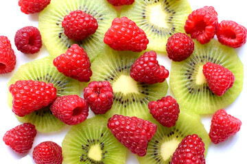 Fruit salad with kiwi slices and ripe raspberries on a white plate. Healthy vegetarian food.