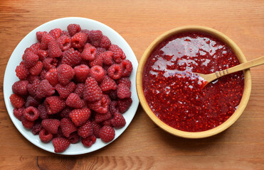 Delicious puree of ripe raspberries in a wooden bowl with a wooden spoon. Ripe raspberries. Flat lay, top view.