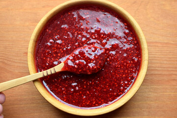Delicious puree of ripe raspberries in a wooden bowl with a wooden spoon. Ripe raspberries. Flat...
