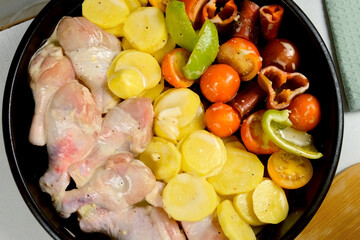 Baking sheet, tray with raw chicken drum sticks, sliced potatoes, vegetables. Prepared ingredients...