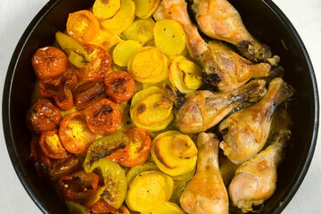 Top view of prepared food baked chicken drum sticks with vegetables on baking tray. Culinary,...